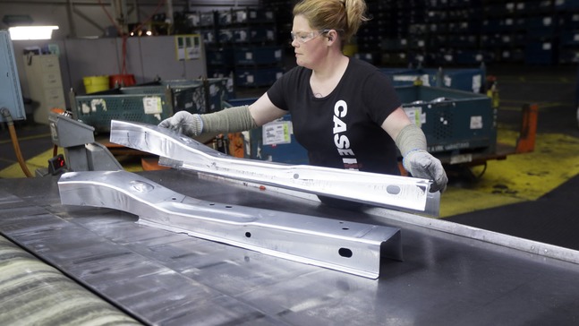 In this April 30, 2015, file photo, United Auto Workers line worker Crystal McIntyre unloads parts from a stamping machine at the General Motors Pontiac Metal Center in Pontiac, Mich. If President Donald Trump delivers on threats to slap 25 percent tariffs on imported automobiles and parts, experts say it will cut auto sales and cost jobs in the U.S., Canada and Mexico. (AP Photo/Carlos Osorio, File)