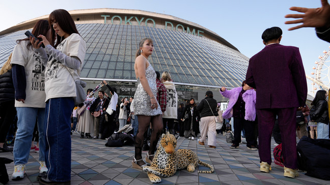 A woman poses for a photo with a stuffed animal of a leopard before Taylor Swift's concert at Tokyo Dome in Tokyo, Saturday, Feb. 10, 2024. (AP Photo/Hiro Komae)