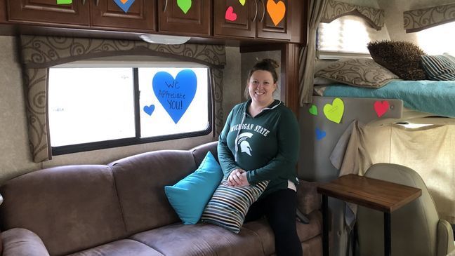 Patty Katje poses on a couch inside the RV. She says neighborhood kids decorated the inside of the RV with paper hearts when it was first delivered. One heart reads, "We appreciate you." (WWMT/Courtesy of Karen Lambert)