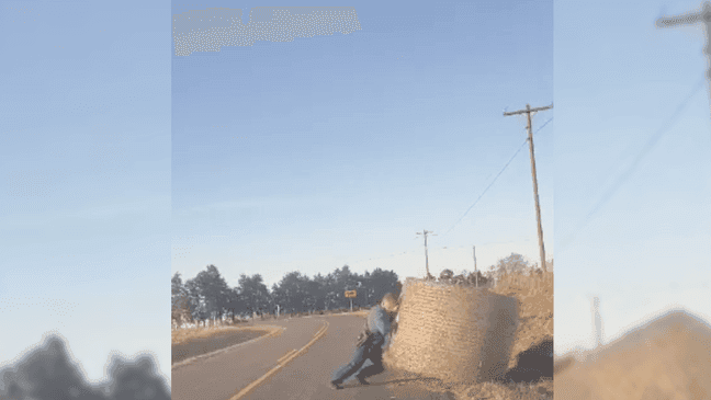 Trooper Isaiah Lemasters moves the hay bale. (Missouri State Highway Patrol.)