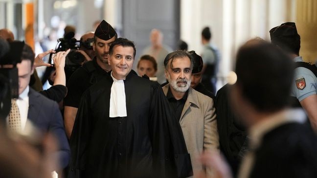 Abderrahmane Ouatiki, center right, who was working as a hotel receptionist, is accompanied by his lawyer Mohand Ouidja, center left, as they arrive for the trial of the 2016 armed robbery of Kim Kardashian, at the palace of justice, Tuesday, May 13, 2025 in Paris. (AP Photo/Aurelien Morissard)