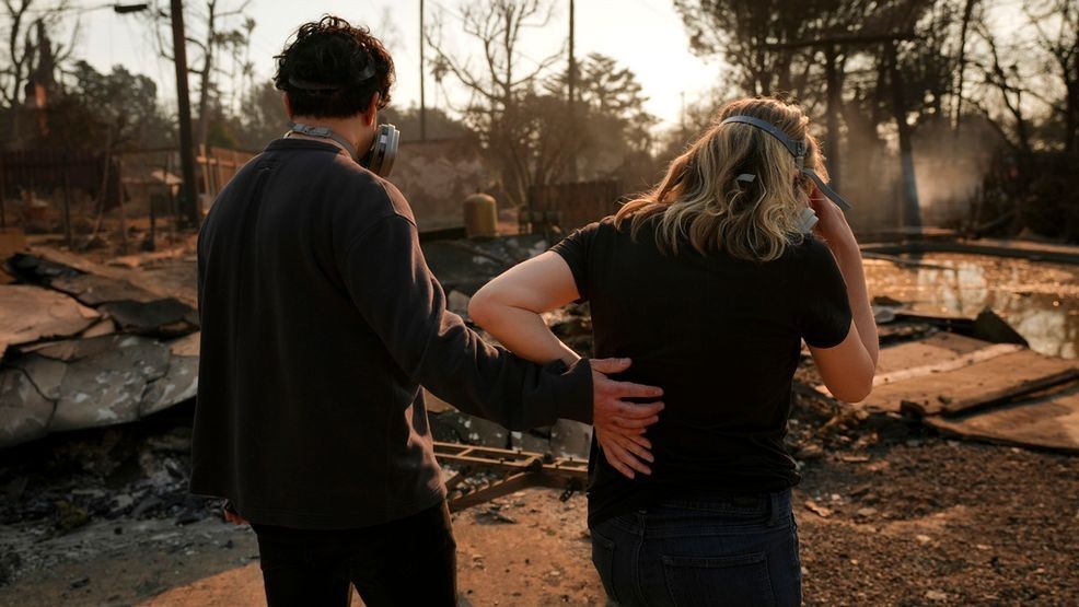 Homeowners Sohrab Nafici, left, and Christine Meinders return to their fire-ravaged neighborhood in the aftermath of the Eaton Fire Friday, Jan. 10, 2025 in Altadena, Calif. (AP Photo/Jae C. Hong)