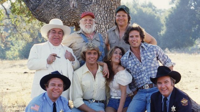 "The Dukes of Hazzard" cast members (Front row, from left) Rick Hurst (as Deputy Cletus Hogg); John Schneider (as Bo Duke); Catherine Bach (as Daisy Duke); Tom Wopat (as Luke Duke) and James Best (as Sheriff Rosco P. Coltraine). Basset hound Sandy (as Flash).  Back row, from left: Sorrell Booke (as Jefferson Davis (J.D.) Hogg); Denver Pyle (as Uncle Jesse Duke) and Ben Jones (as Cooter Davenport). (Photo by CBS via Getty Images)