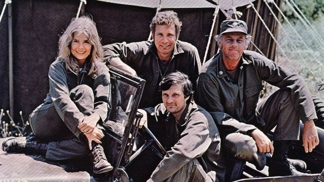 American actor, director and writer Alan Alda in the driving seat of a jeep, surrounded by Loretta Swit and other cast members of the hit television show M.A.S.H, in costume as members of a US Army medical corp.   (Photo by Keystone/Getty Images)