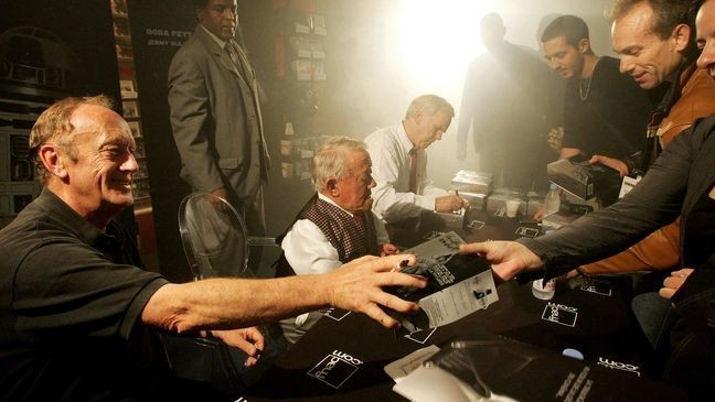 Fans of Star Wars trilogy movies ask actors Kenneth Colley (L) alias Admiral Piett, Kerny Baker (C) alias R2-D2 and Jeremy Bulloch alias Boba Fett to sign autographs on their DVD box during the first sale at a famous store of Les Champs Elysees in Paris, early 21 September 2004.  AFP PHOTO / THOMAS COEX (Photo by THOMAS COEX / AFP) (Photo by THOMAS COEX/AFP via Getty Images)