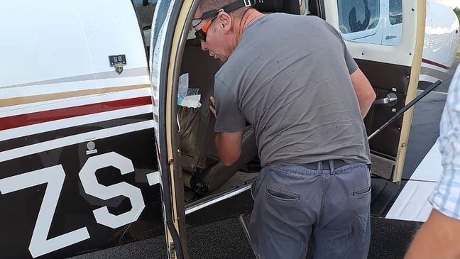 FILE - In this photo provided by Brian Emmenis, fire officer and snake handler Johan de Klerk looks inside a plane, in Welkom, South Africa, as he searches for a venomous snake that the pilot found hiding under his seat midair, Monday April 3, 2023.{&nbsp;} (Brian Emmenis via AP)