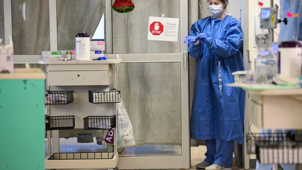 FILE PHOTO: A nurse puts on rubber gloves before entering a COVID-19 patient's room. (AP Photo/Julie Bennett)