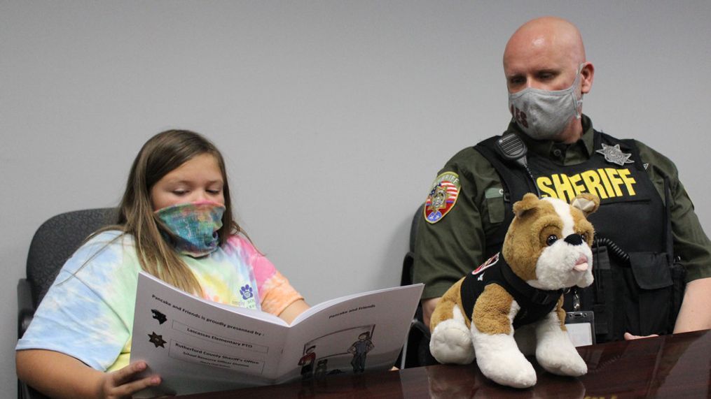 4th-grade student Emma Maxwell reads the “Pancake and Friends” book to author SRO Chad Dodson at Lascassas Elementary School. (Rutherford Co. Sheriff's Office photo){p}{/p}