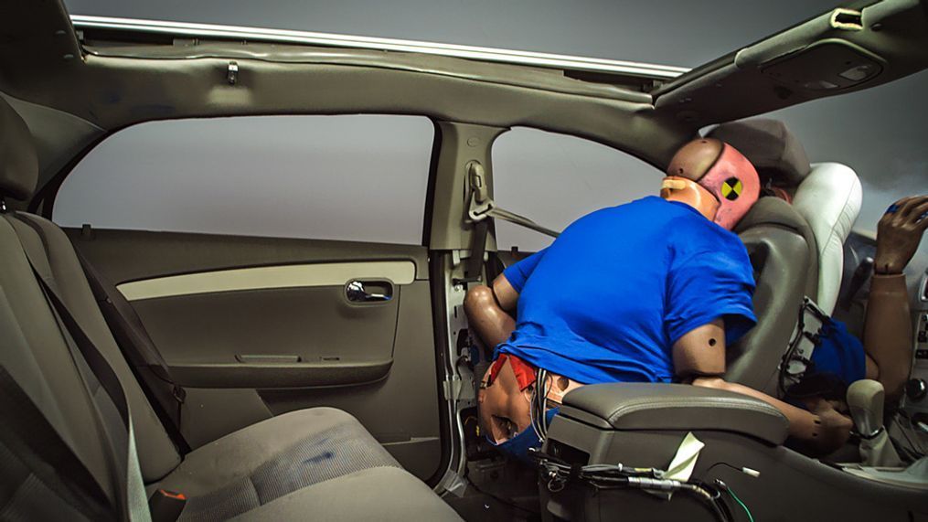 IIHS sled tests show why it is crucial to buckle up, even in back. IIHS engineers placed an unbelted test dummy in the back seat behind the belted driver dummy. Without a safety belt to control its movement during the crash, the rear-seat dummy slammed into the back of the driver seat, sandwiching the driver dummy between the seat and front airbag. In a real crash like this, both the driver and passenger likely would be injured. (Image courtesy of the Insurance Institute for Highway Safety)