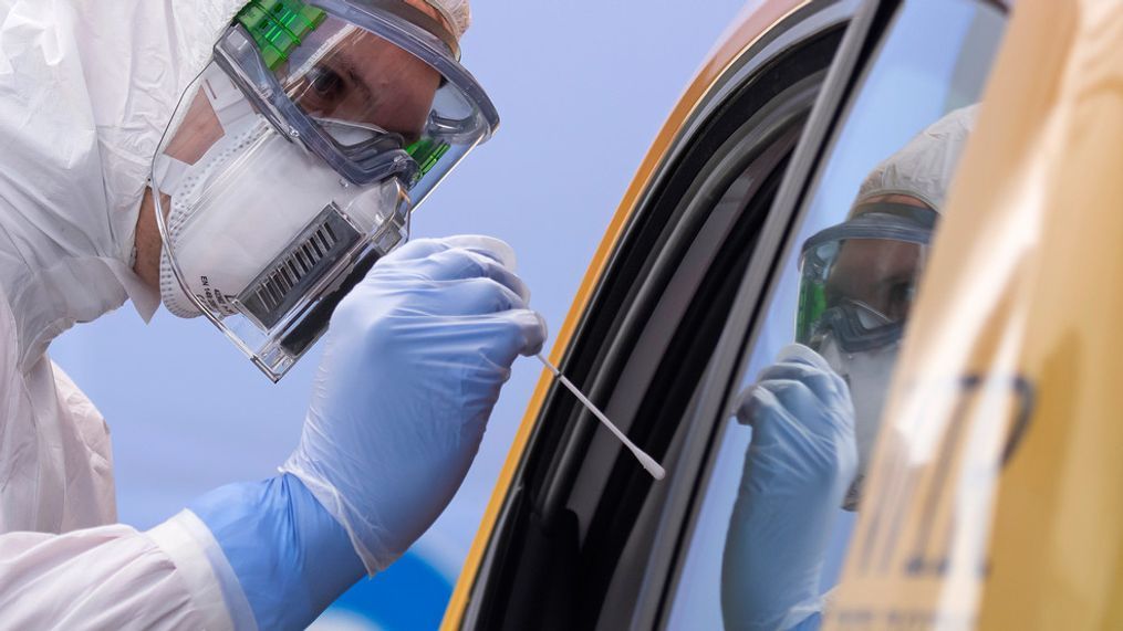 FILE - In this April 15, 2020, file photo, helper of the German Red Cross DRK in protective suit, left, takes a smear from a patient in his car during the official opening of a drive-thru COVID-19 testing center at the fair ground in Dresden, eastern Germany. (AP Photo/Jens Meyer, File)