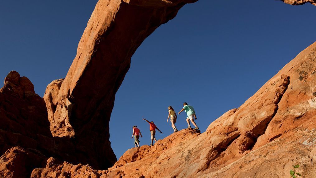 Family of four walking on the rocks in Arches National Park in Utah. 