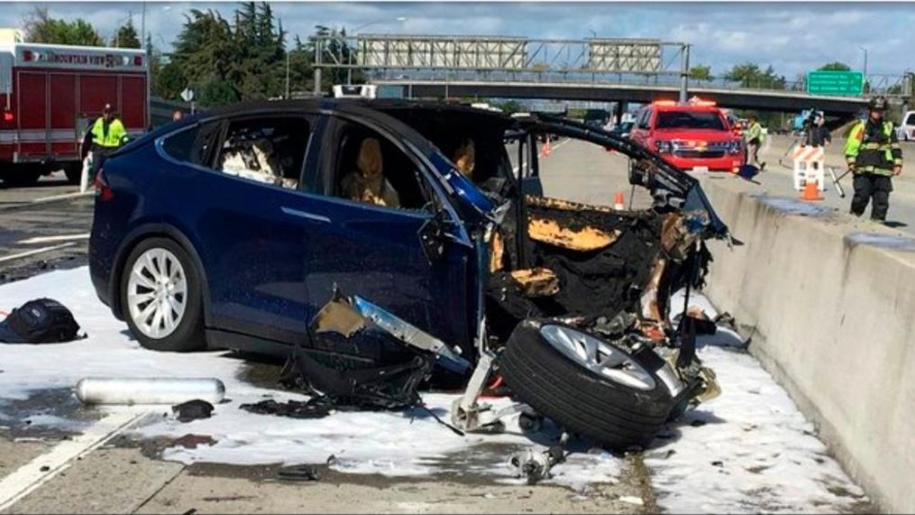 FILE - In this March 23, 2018 file photo provided by KTVU, emergency personnel work a the scene where a Tesla electric SUV crashed into a barrier on U.S. Highway 101 in Mountain View, Calif.  Tesla says, Saturday, March 31,  the vehicle in a fatal crash last week in California was operating on Autopilot, the latest accident to involve self-driving technology. The automaker says the driver, who was killed in the accident, did not have his hands on the steering wheel for six seconds before the crash. Tesla says its Autopilot feature, which can keep speed, change lanes and self-park, requires drivers to keep their eyes on the road and hands on the wheel to take control of the vehicle to avoid accidents. (KTVU via AP)