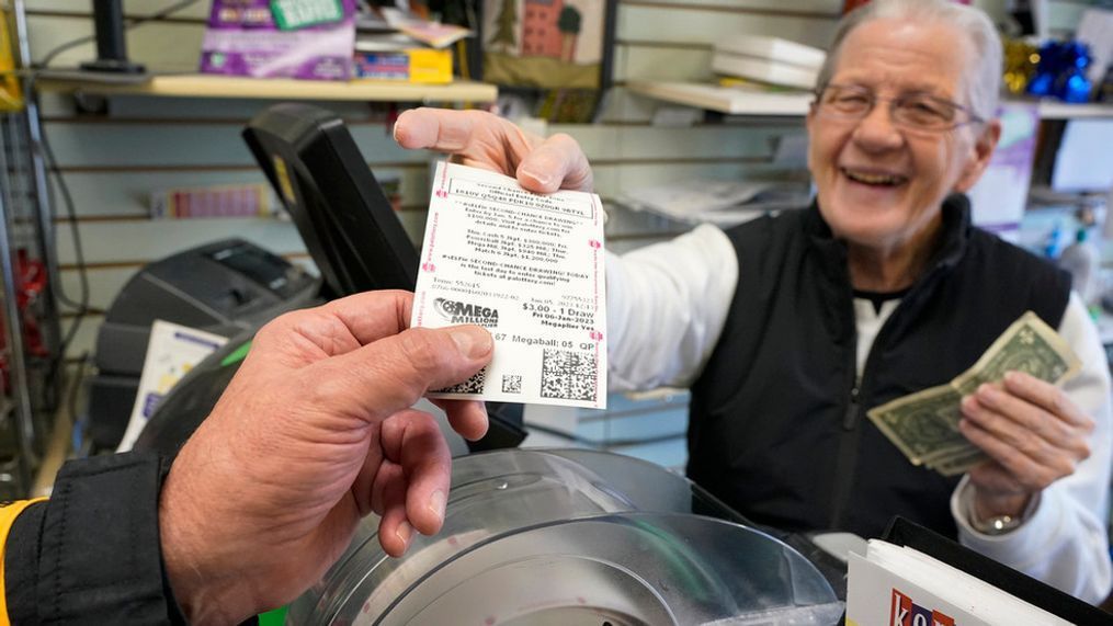 FILE - Dot Skoko, owner of Dot's Dollar More or Less shop in Mt. Lebanon, Pa., hands a customer a Mega Millions lottery ticket, Thursday, Jan. 5, 2022. (AP Photo/Gene J. Puskar, File)