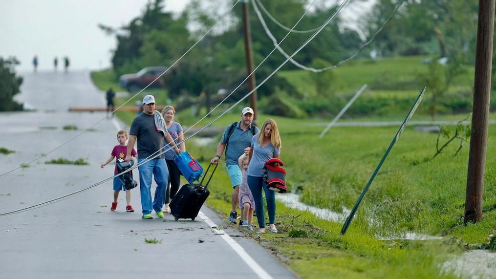 A family ducks under power lines as they make their way out of a tornado damaged neighborhood after being hit on Tuesday, May 28, 2019, south of Lawrence, Kan., near US-59 highway and N. 1000 Road. The past couple of weeks have seen unusually high tornado activity in the U.S., with no immediate end to the pattern in sight.(Chris Neal/The Topeka Capital-Journal via AP)