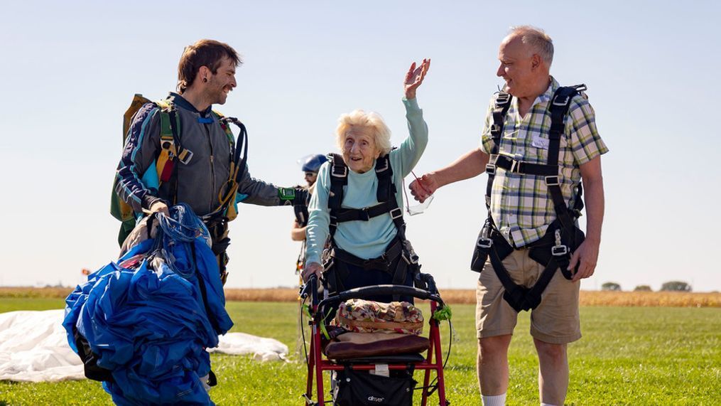 Dorothy Hoffner, 104, waves to the crowd with tandem jumper Derek Baxter, left, and friend Joe Conant after becoming the oldest person in the world to skydive Sunday, Oct. 1, 2023, at Skydive Chicago in Ottawa, Ill. (Brian Cassella/Chicago Tribune via AP)