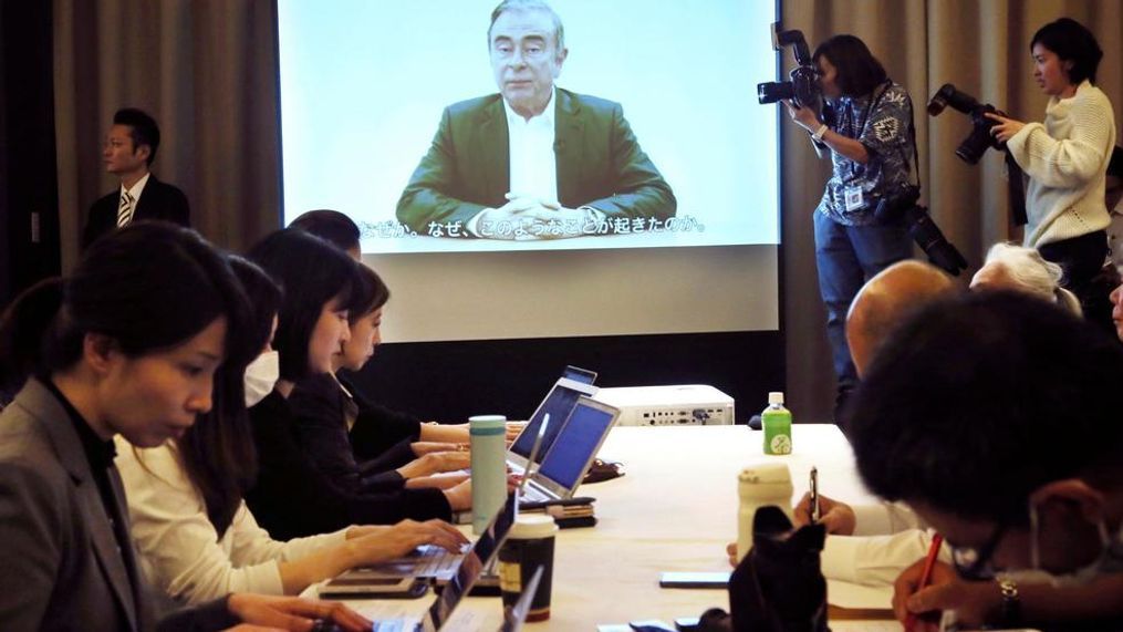 Journalists attend a press conference with Nissan's former Chairman Carlos Ghosn, seen on a screen, speaking in a video in Tokyo, Tuesday, April 9, 2019. Ghosn is maintaining he is innocent and in a video released by his legal team accuses some executives at the Japanese automaker of a "conspiracy" that led to his arrest on financial misconduct allegations. (AP Photo/Koji Sasahara)