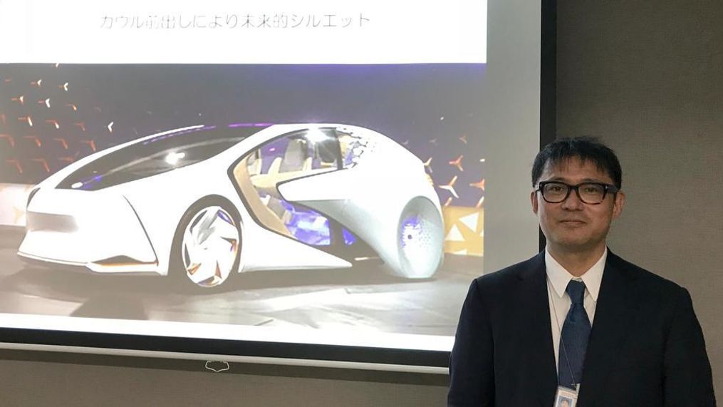 Toyota Motor Corp. manager Makoto Okabe stands in front of a image of the concept car "TOYOTA Concept-i" series Monday Oct. 16, 2017 in Tokyo. The use of artificial intelligence means cars may get to know drivers as human beings by analyzing their facial expressions, driving habits and social media use. (AP Photo/Yuri Kageyama)