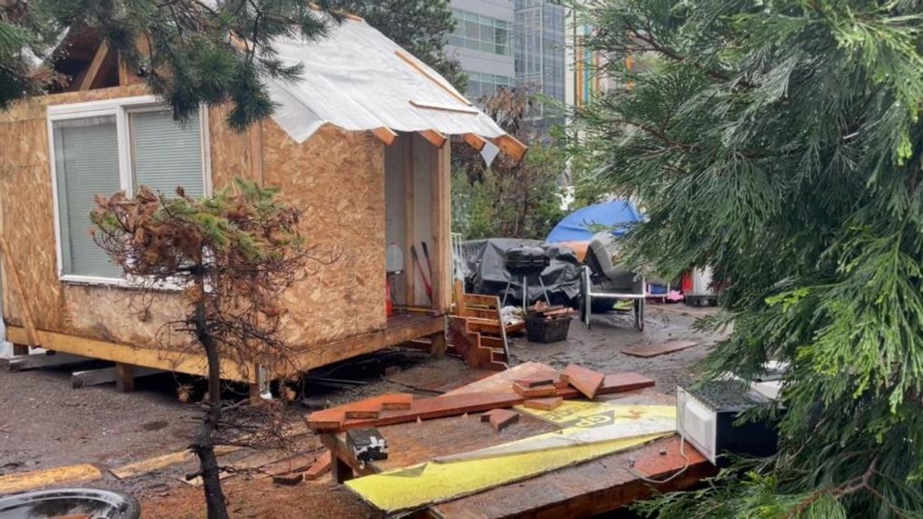 An encampment of the unhoused at Fairview Ave and Mercer Street in Seattle, where two people are building a tiny house. (KOMO)