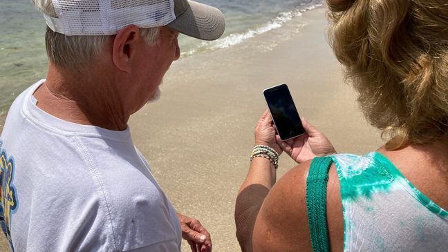 The Martins holding up the iPhone they found in the surf. (Photo: CBS12)