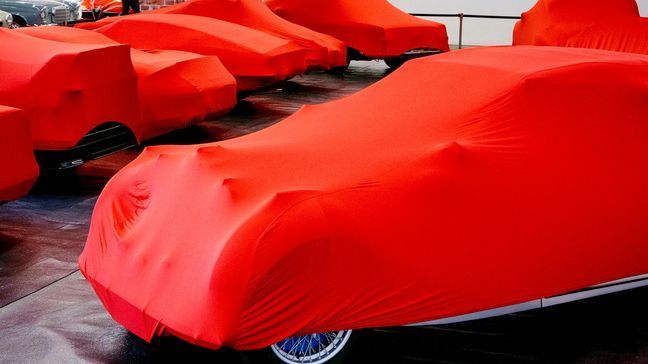 Cars are covered with red sheets ahead of the start of the IAA Auto Show in Frankfurt, Germany, Sunday, Sept. 8, 2019. (AP Photo/Michael Probst)