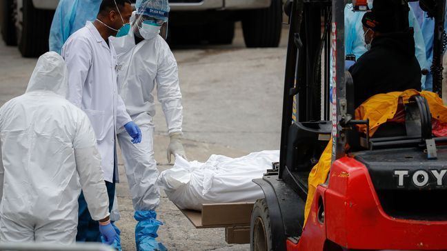 A body wrapped in plastic is prepared to be loaded onto a refrigerated container truck used as a temporary morgue by medical workers due to COVID-19 concerns, Tuesday, March 31, 2020, at Brooklyn Hospital Center in the Brooklyn borough of New York. (AP Photo/John Minchillo)