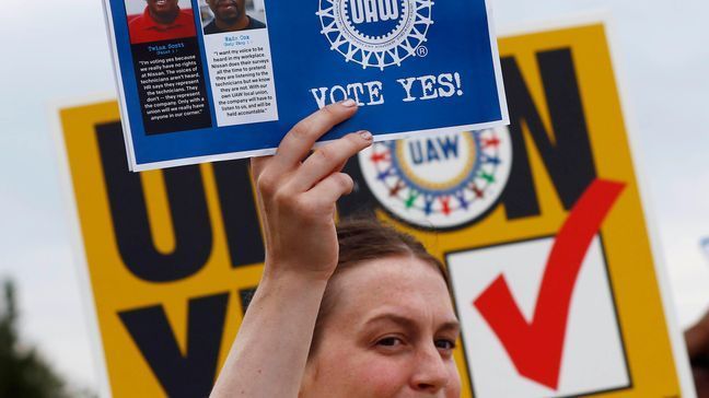 In this Tuesday, Aug. 1, 2017, photo, a UAW member holds up a flyer to be given to Nissan workers as they leave the Nissan vehicle assembly plant in Canton, Miss. Union members met most shifts arriving and leaving waving posters, flyers and singing union chants at each of the plant's employee entrances. In voting that begins early Thursday, Aug. 3, some 3,700 direct employees at Nissan Motor Co.'s car and truck assembly plant in Canton will decide whether they want a union. The polls close at 7 p.m., local time on Friday. (AP Photo/Rogelio V. Solis)