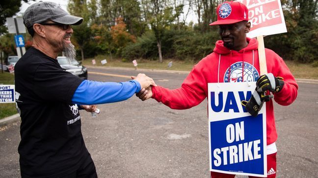 Picketing United Auto Workers Richard Rivera, left, and Will Myatt react to news of a tentative contract agreement with General Motors, in Langhorne, Pa., Wednesday, Oct. 16, 2019. Bargainers for General Motors and the United Auto Workers reached a tentative contract deal on Wednesday that could end a monthlong strike that brought the company's U.S. factories to a standstill. (AP Photo/Matt Rourke)