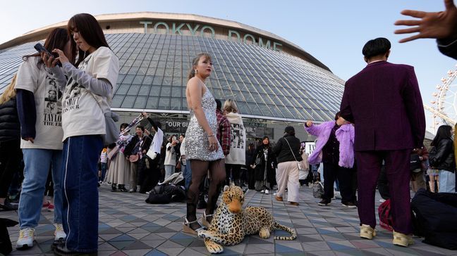 A woman poses for a photo with a stuffed animal of a leopard before Taylor Swift's concert at Tokyo Dome in Tokyo, Saturday, Feb. 10, 2024. (AP Photo/Hiro Komae)