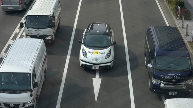 In this Wednesday, Feb. 21, 2018, photo, Nissan Motor Co.'s Easy Ride robo-vehicle, center, goes on a course during a test ride in Yokohama, near Tokyo. Starting next month, Nissan is testing on regular roads what it calls “a robo-vehicle mobility service.” Called Easy Ride, it uses a cell-phone app to book semi-autonomous driven rides. (AP Photo/Shizuo Kambayashi)