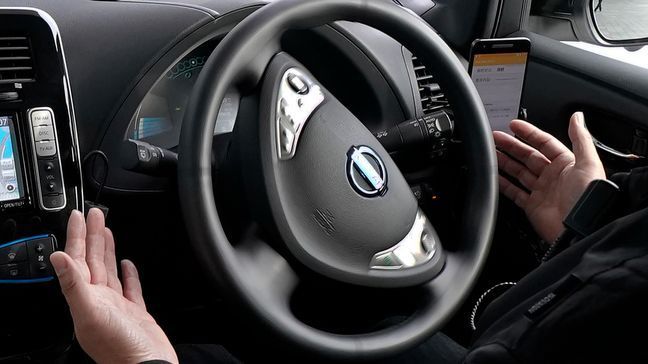 In this Wednesday, Feb. 21, 2018, photo, Nissan Motor Co.'s staff member gets his hands off of the steering wheel of its Easy Ride robo-vehicle during a test ride on a course in Yokohama, near Tokyo. Starting next month, Nissan is testing on regular roads what it calls “a robo-vehicle mobility service.” Called Easy Ride, it uses a cell-phone app to book semi-autonomous driven rides. (AP Photo/Shizuo Kambayashi)