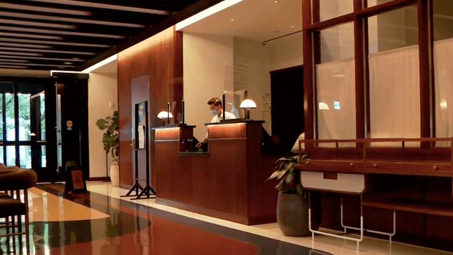 FILE - Man wearing a mask behind a desk at the lobby of a Northwest Washington, D.C. hotel, Easton DC. (WJLA)